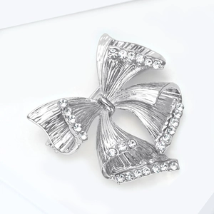 Détail de la broche nœud argentée ornée de strass avec une texture en métal brossé