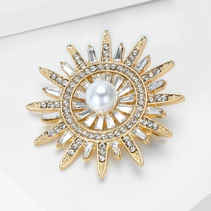 Détail macro de la broche soleil avec perle centrale et zircons blancs éclatants