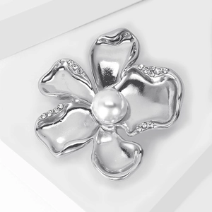 Close-up of a silver flower brooch with sparkling rhinestones and a white pearl core