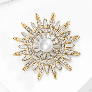 Vue macro d'une broche solaire avec perle centrale, cristaux et rayons dorés polis