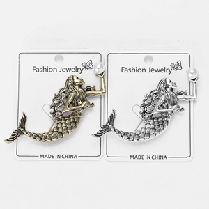 Detailed close-up of retro mermaid brooches in antique gold and silver with imitation pearls