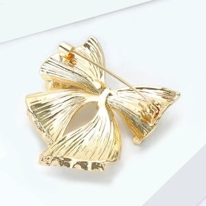 Détails du dos d'une broche nœud dorée montrant l'épingle de sécurité et la texture striée