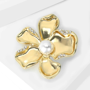 Close-up of elegant gold flower brooch with white pearl center and sparkling crystals