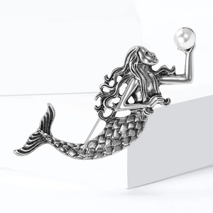 Vintage silver mermaid brooch with white pearl accent on a minimalist pedestal