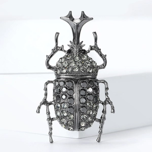 Vintage beetle brooch with grey rhinestones and dark metal finish on a white background