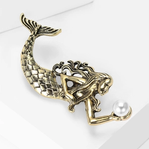 Close-up of vintage gold mermaid brooch with detailed scales and white pearl accent