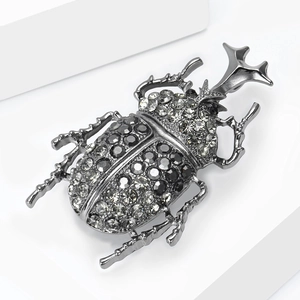 Macro detail of vintage beetle brooch featuring intricate rhinestone inlay and dark metal base