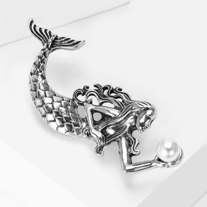 Detailed close-up of a vintage mermaid brooch with elegant scales and a white pearl accent