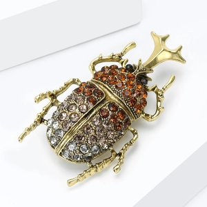 Detailed close-up of a vintage beetle brooch with amber rhinestones and gold finish