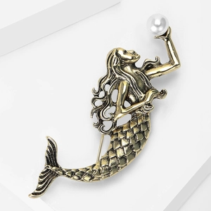Close-up of vintage mermaid brooch featuring antique bronze texture and a white pearl