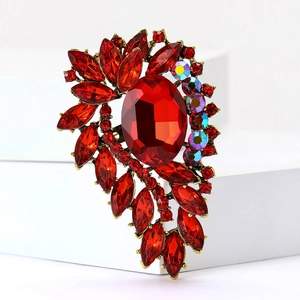 Vintage gold brooch featuring a large oval red gemstone and radiant sparkling rhinestones