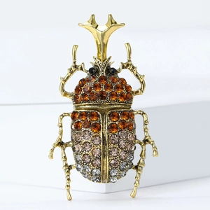 Vintage gold beetle brooch with amber rhinestones on minimalist white display