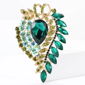 Detailed macro view of vintage gold alloy brooch with deep green pear-shaped gemstones