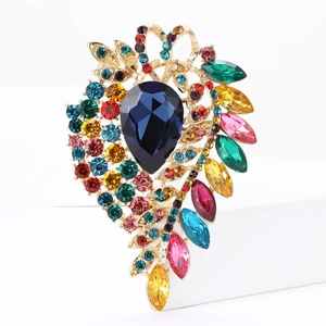 Macro shot of colorful crystal brooch with blue teardrop stone and gold alloy base