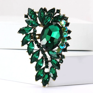 Detailed macro view of vintage gold alloy brooch with emerald green crystals and rhinestones