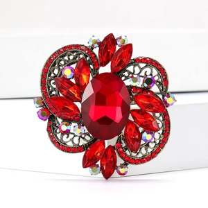 Macro shot of vintage alloy brooch with large oval red gemstone and crystal petals
