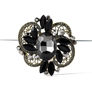 Close-up of vintage baroque alloy brooch with oval gray gemstone and black petals