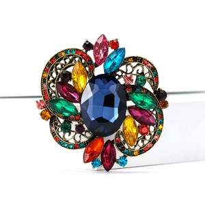 Macro detail of luxury vintage brooch with a deep blue centerpiece and colorful rhinestones