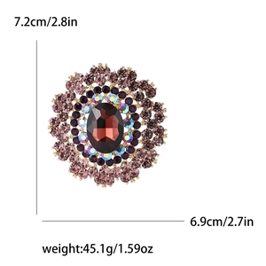 Detail view of large vintage brooch with red-brown center stone and colorful rhinestones