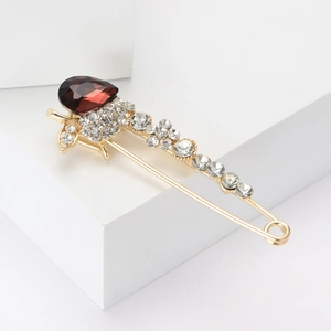 Broche élégante en cristal doré avec pierre rouge en goutte sur base géométrique