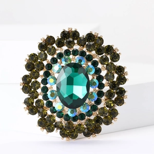 Detailed close-up of luxurious flower brooch with emerald green crystal and gold finish