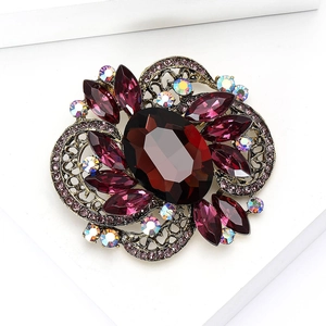 Vintage gold brooch with large red oval gemstone and purple marquise crystals on white base