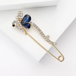 Détail de la broche épingle dorée ornée de cristaux bleu foncé et de strass blancs