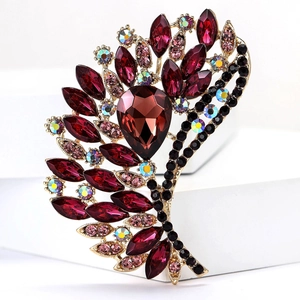 Detail view of retro wing-shaped alloy brooch with burgundy crystals and red gemstone