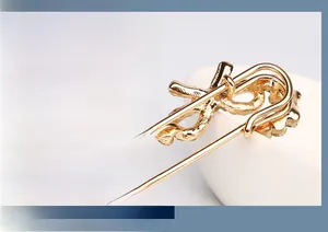 Détail d'une broche vague dorée ornée d'accents en cristal étincelants et d'une texture