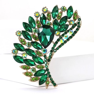 Detailed close-up of dark green and AB crystal feather-shaped brooch in gold setting