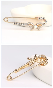 Détail macro d'une broche épingle dorée avec des cristaux blancs et irisés en nœud