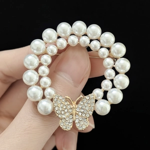 Vue détaillée de la broche couronne de perles à double couche avec papillon doré et strass