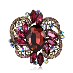 Vintage style gold brooch featuring a deep red oval gem and pink crystals on white backdrop