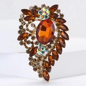 Detail view of large oval orange gemstone brooch with amber rhinestones on gold alloy base