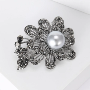Broche rose rétro en métal gris avec cristaux fumés et perle sur socle blanc