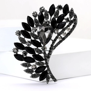 Macro detail of retro fan-shaped alloy brooch with large grey crystal and black rhinestones