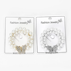 Détail de broches couronne en perles et papillon en fini or et argent sur cartes