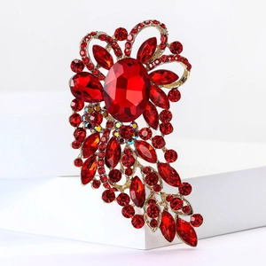 Close-up of vintage gold alloy brooch featuring a large red crystal and floral rhinestones