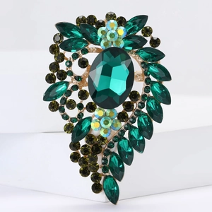Macro shot of luxury emerald glass brooch with sparkling rhinestones on golden alloy base