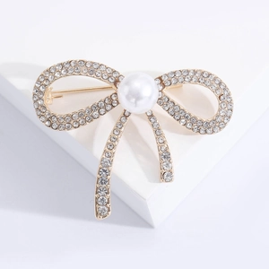 Broche nœud élégante avec cristaux scintillants et perle sur support blanc pur