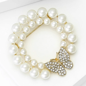 Détail de la broche couronne de perles avec un papillon doré orné de strass brillants