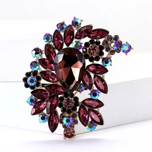 Close-up of vintage flower brooch with deep red pear-shaped rhinestones and gold base