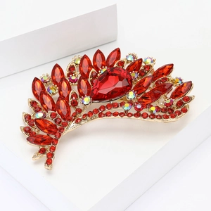 Vintage gold alloy brooch with deep red crystals and teardrop rhinestones on white pedestal