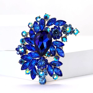 Close-up of vintage alloy brooch featuring a large pear-shaped blue crystal centerpiece
