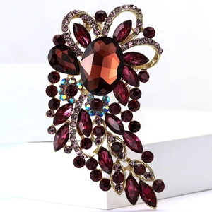 Macro detail of ornate vintage gold brooch with large dark red gems and AB rhinestones