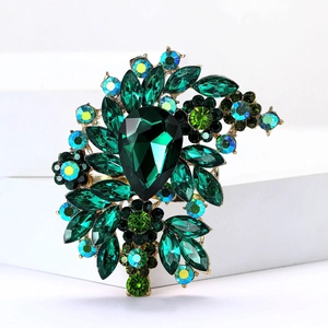 Macro detail of luxury vintage brooch featuring emerald green crystals and gold alloy base