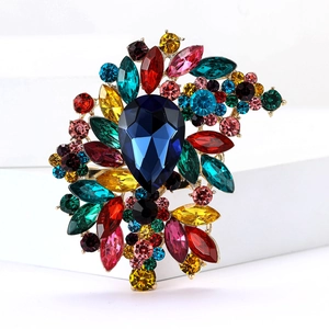 Macro detail of high-end colorful rhinestone brooch with deep blue teardrop gem and gold base