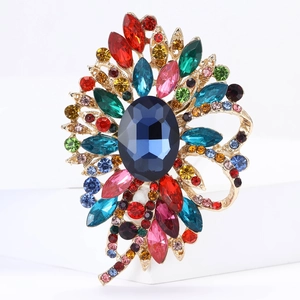 Detailansicht einer luxuriösen Blumenbrosche mit blauem Stein und bunten Kristallen
