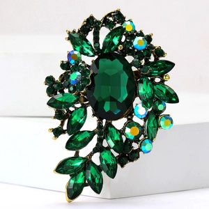 Detalle de broche vintage con cristales verdes y pedrería sobre base de metal bronce