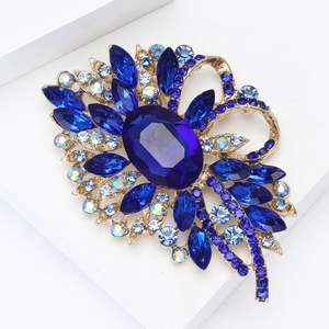 Makroaufnahme einer luxuriösen goldfarbenen Blumenbrosche mit großen blauen Kristallblüten
